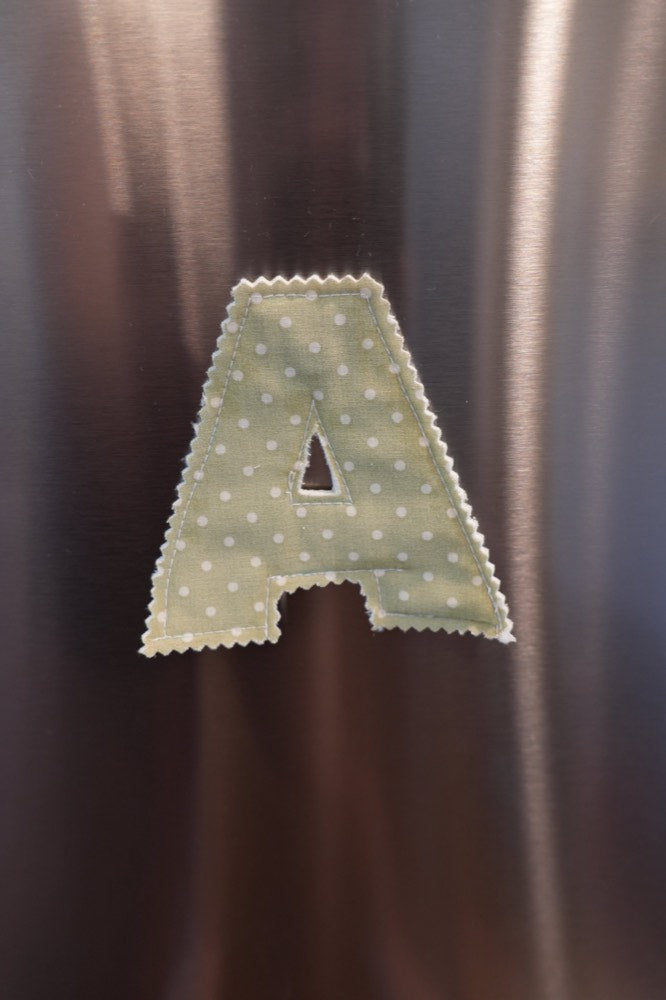 Finished fabric letter A held on a refrigerator door by a sewn-in waterproof neodymium magnet